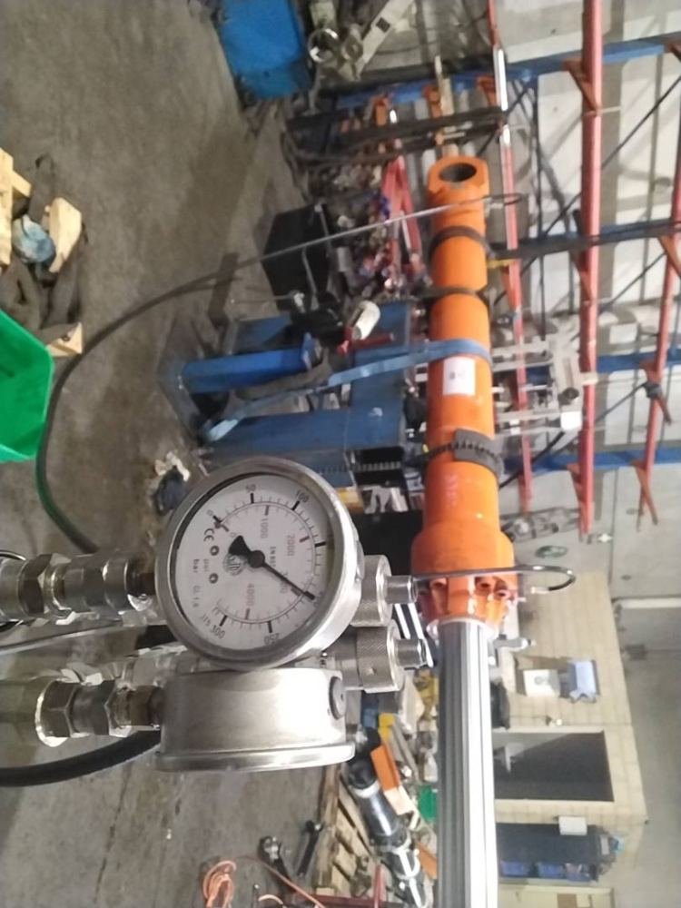 Pressure gauge testing an orange hydraulic cylinder